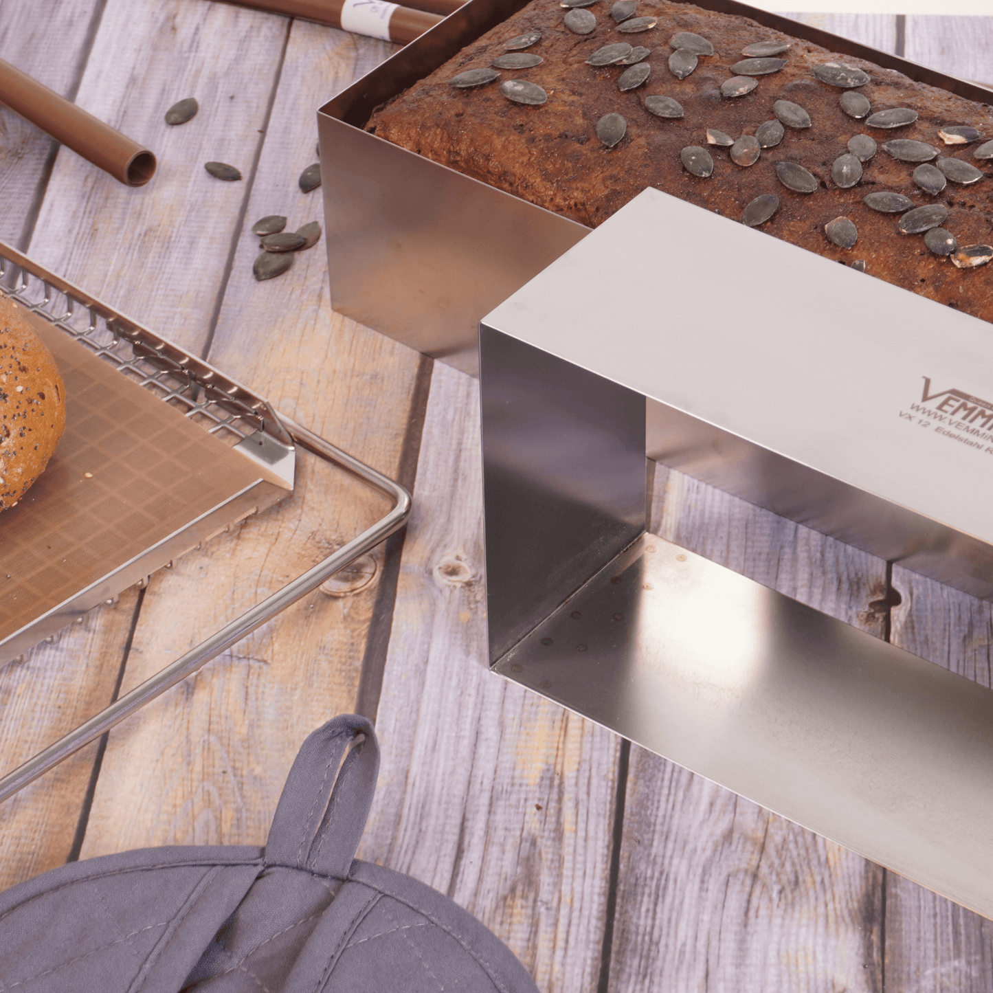 Brot-Profi stainless steel bread mold with a loaf topped with pumpkin seeds on a wooden surface.